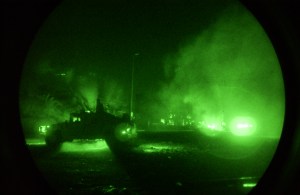 Smoke rises behind a Charlie Company HUMVEE from a car that charged the scene firing at the unit. Charlie Company returned fire, stopping the car, to secure the area, during increased tension in Sadr City, Iraq on July 5, 2004. U.S. Air Force photo by Staff Sgt Ashley Brokop (Released)